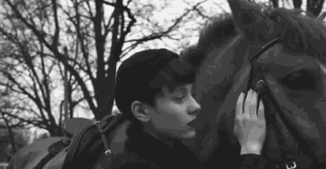 a black and white photo of a person petting a horse .