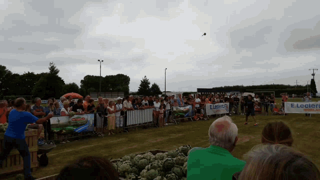 a crowd of people are watching a man throw a frisbee in front of a banner that says e.leclerc