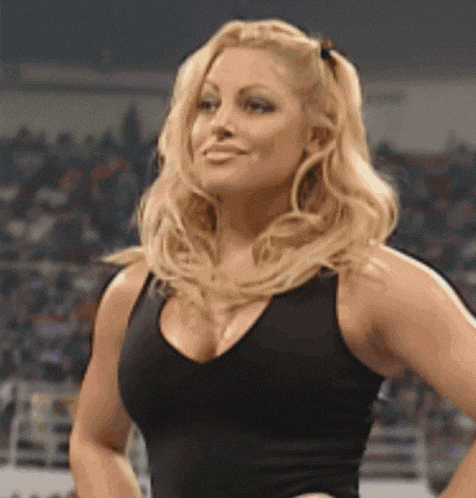 a woman in a black tank top is standing in front of a crowd in a stadium .