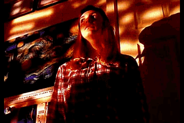 a woman in a plaid shirt is standing in front of a wall with a picture on it .