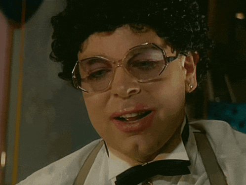 a woman wearing glasses and a bow tie looks at the camera