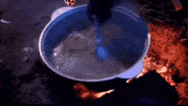 a person is pouring water into a pot with a spoon