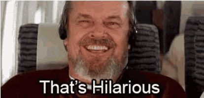 a man with a beard is wearing headphones and smiling while sitting on a plane .