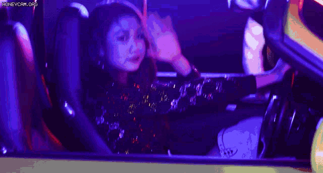 a woman in a sequined dress is sitting in the driver 's seat of a car .