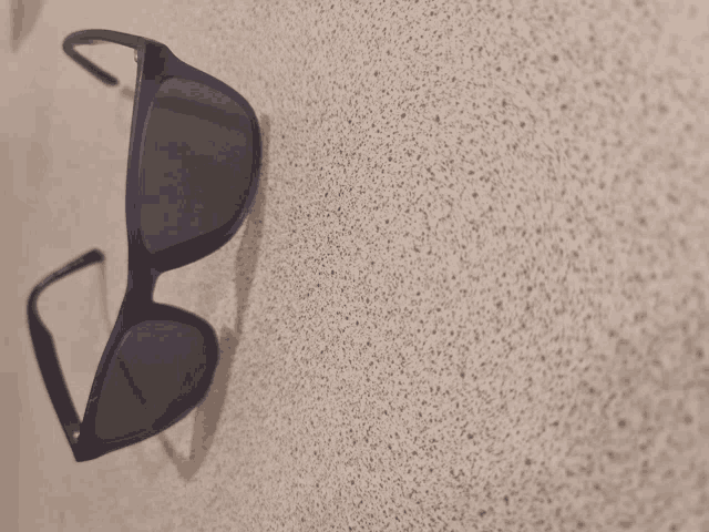 a pair of sunglasses are hanging on a white wall