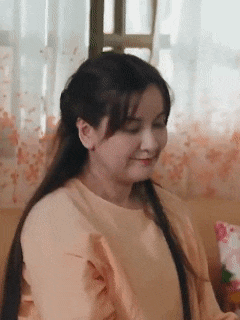 a woman is sitting on a couch in a living room and smiling .