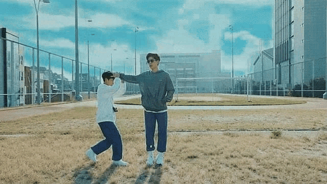 two men are standing in a field holding hands and dancing .