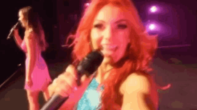 two women are singing into microphones on a stage .