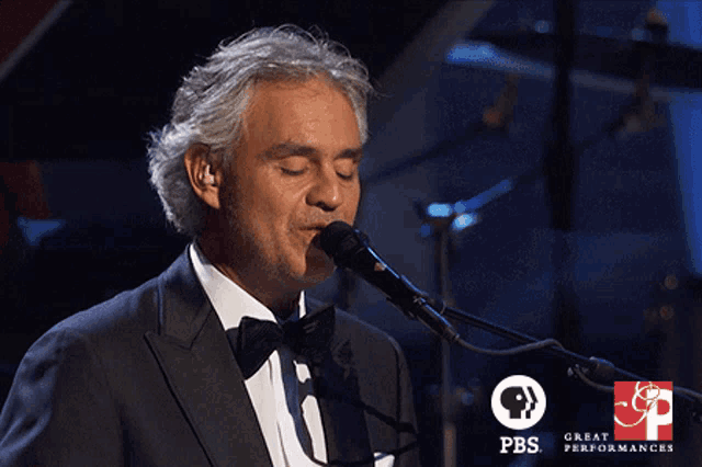 a man in a tuxedo singing into a microphone with the words thank you below him
