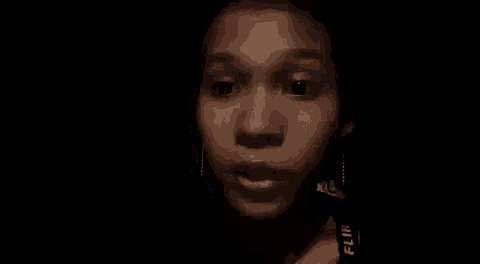 a close up of a woman 's face in a dark room with a black background .