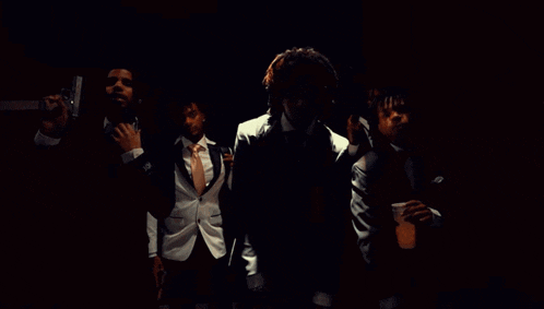 a group of men in suits and ties are dancing together