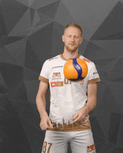 a man with the number 87 on his shorts holds a volleyball