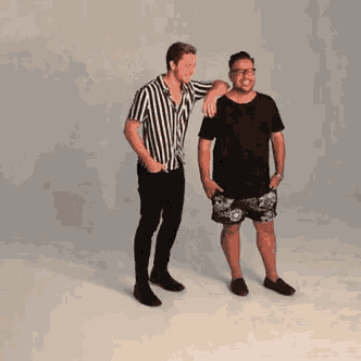 two men are standing next to each other with one wearing a striped shirt