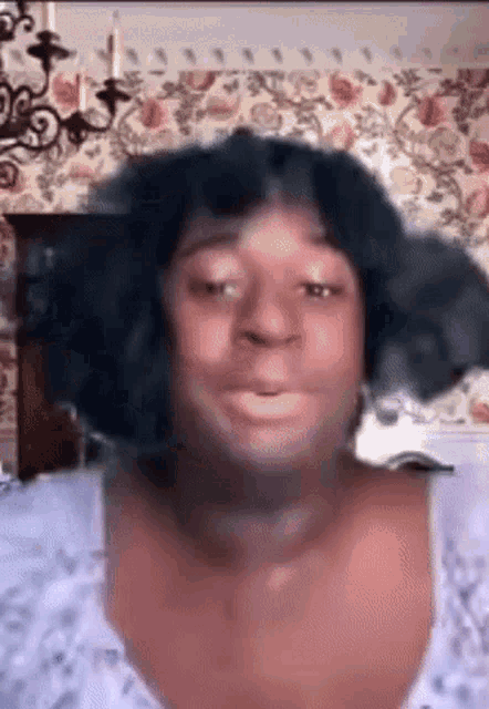 a woman with a wig on her head is making a funny face in a room .