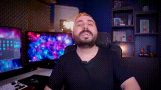 a man with a beard is sitting in a chair in front of a computer monitor .