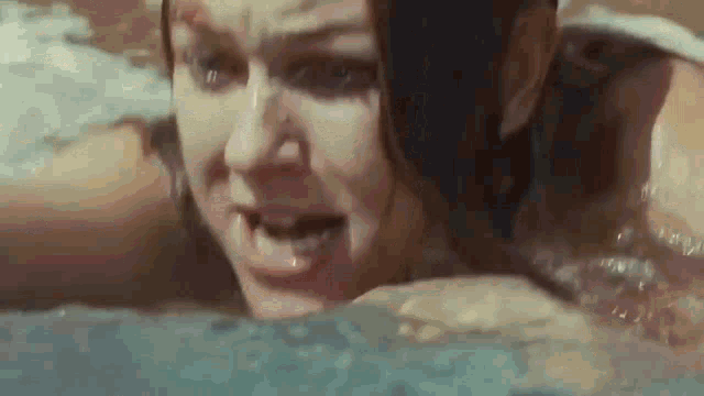 a woman is swimming in a pool with her mouth open and her eyes closed .