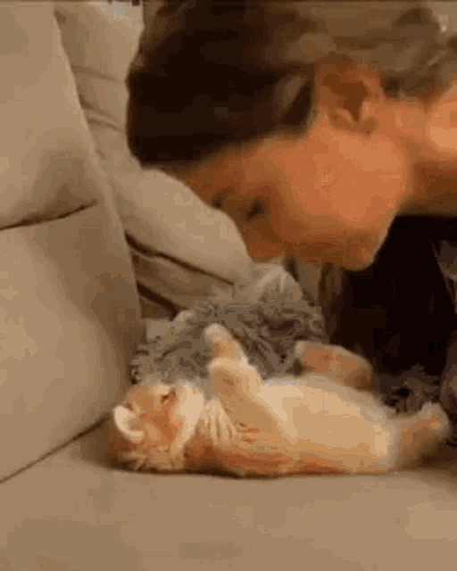 a woman is laying on a couch with a kitten on her lap .