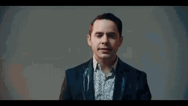 a man in a suit and polka dot shirt is making a face .