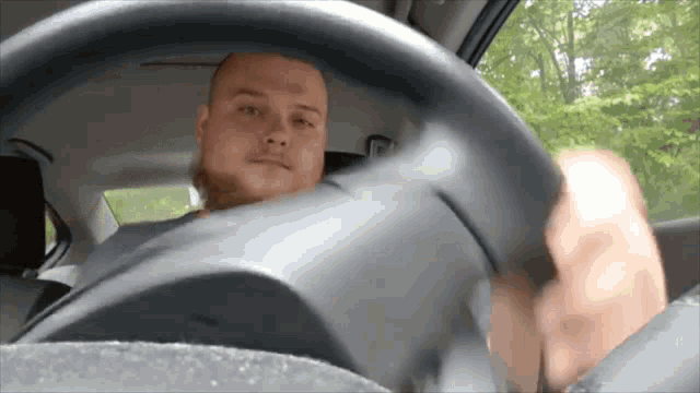 a man is driving a car and looking at the camera
