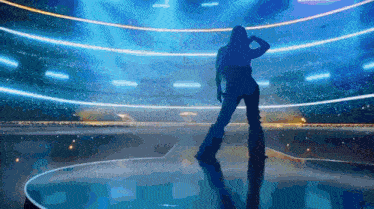 a silhouette of a woman dancing on a stage in a stadium
