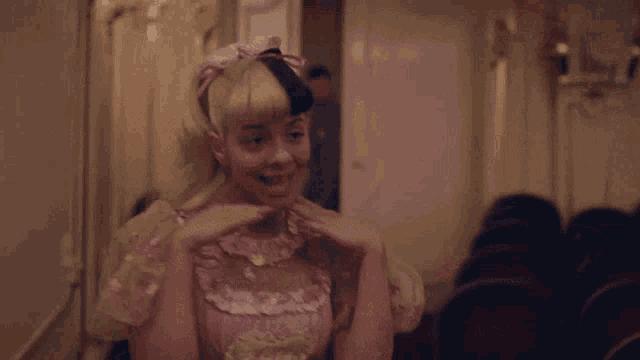 a woman in a pink dress is sitting in front of a crowd in a theater .