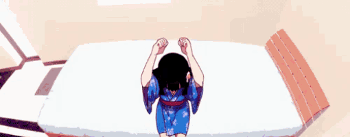 a person is laying on a bed with their head on their knees .