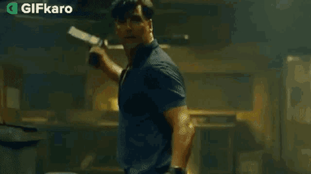 a man in a blue shirt is holding a gun in his hand .