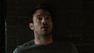 a man in a grey shirt is screaming with his mouth open