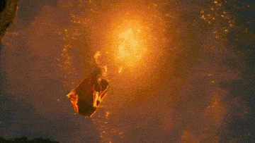 a person is flying through the air in front of a large fire .