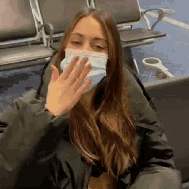 a woman wearing a face mask is sitting in a waiting room .