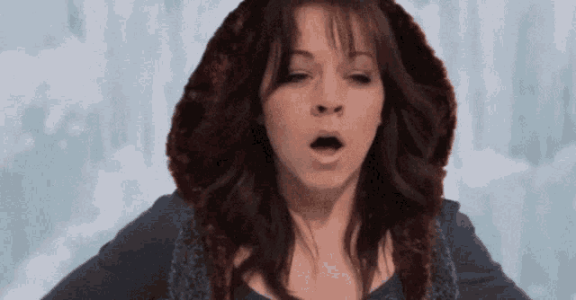a woman wearing a fur hooded jacket is making a funny face .