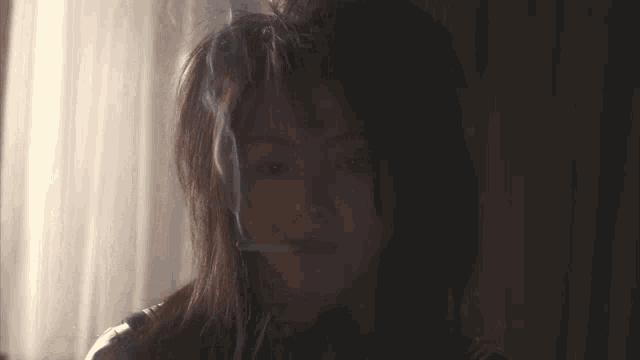 a woman is smoking a cigarette in a dark room