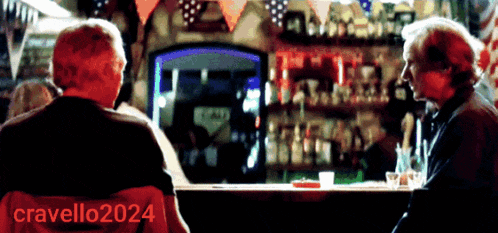 two men are sitting at a bar with the name cravello2024 on the back of their chair