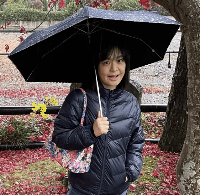 a woman in a blue jacket holds an umbrella over her head