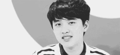a black and white photo of a young man with curly hair making a funny face .
