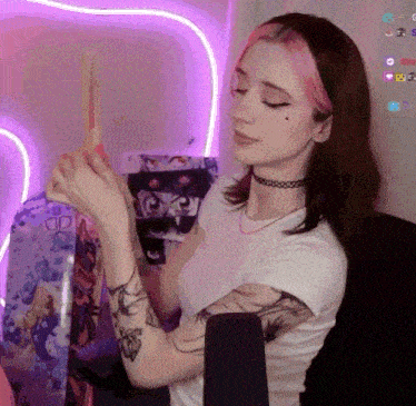 a woman with pink hair is sitting in a chair holding a stick in her hand .