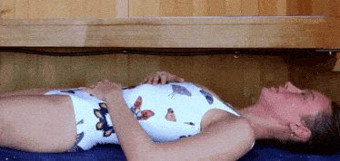 a woman in a bathing suit with butterflies on it is laying on her back