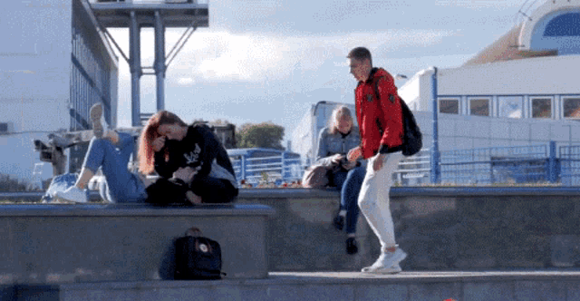 a man in a red jacket is walking by a group of people