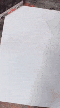 a person is painting on a piece of paper with a bottle of ecoline in the background