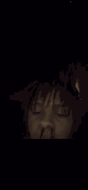 a close up of a person 's face in the dark with their hand on their nose .