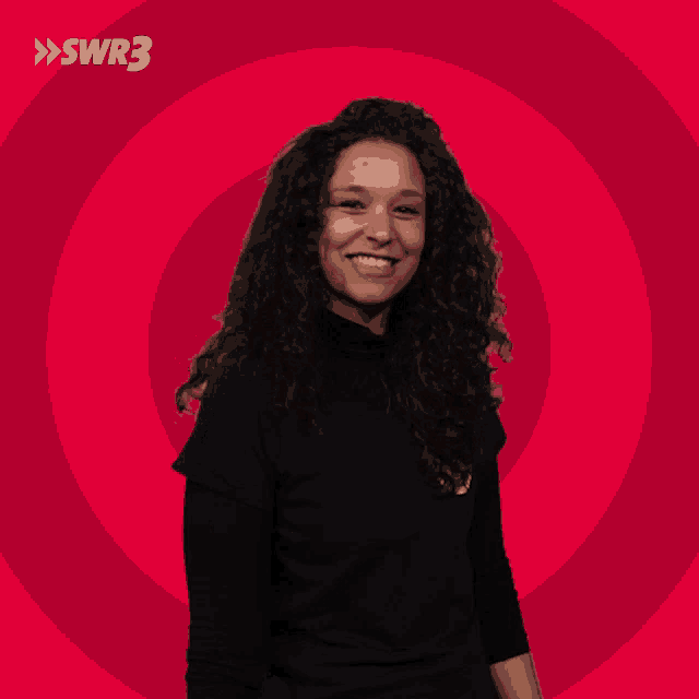 a woman with curly hair is smiling in front of a red circle with swr3 written on it
