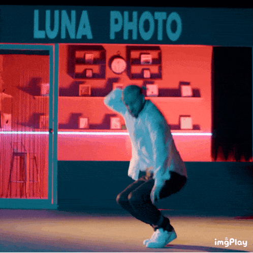 a man is squatting in front of a luna photo store