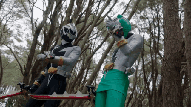 two power rangers are standing in the woods holding a sword