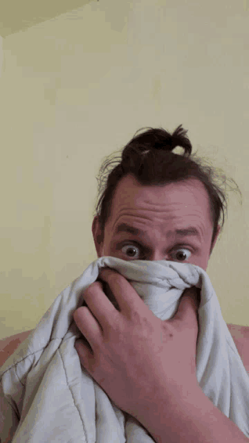 a man covering his face with a blanket and making a funny face
