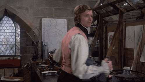 a man in a pink vest is standing in front of a drawing of a body