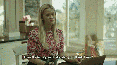 a woman is sitting at a table with a laptop and a glass of wine and talking to someone .