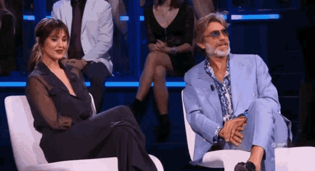 a man in a blue suit sits next to a woman in a black suit