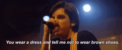 a man singing into a microphone with the words " you wear a dress and tell me not to wear brown shoes " next to him