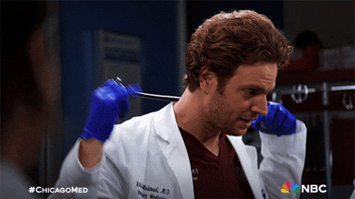 a man in a lab coat and blue gloves is holding a stethoscope and says #chicagomed on the bottom right