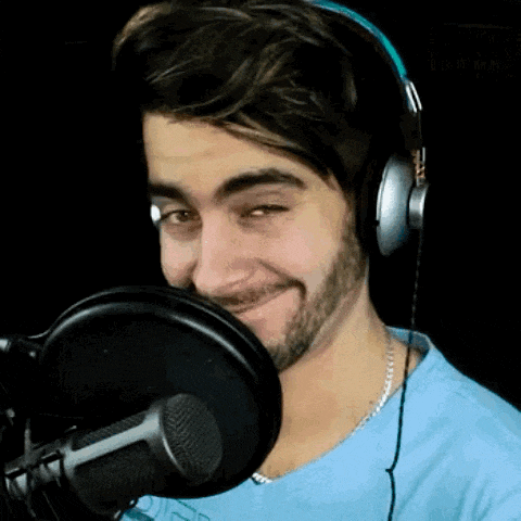 a man wearing headphones stands in front of a microphone and smiles